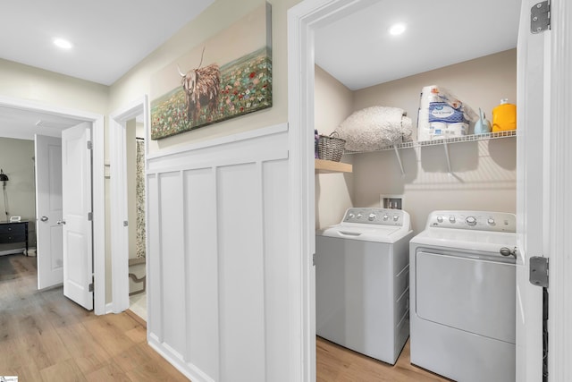 laundry area with light hardwood / wood-style flooring and washer and dryer