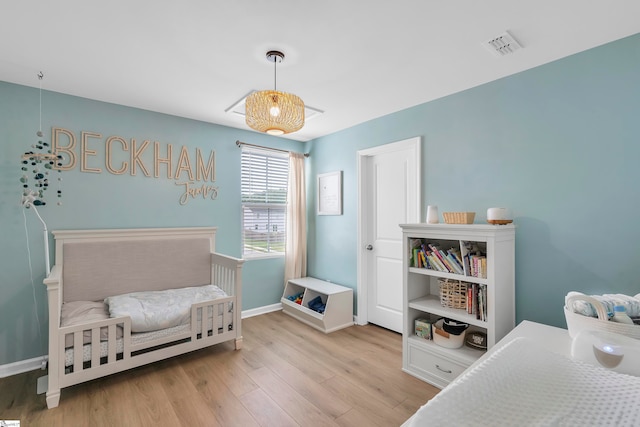 bedroom with light hardwood / wood-style flooring and a nursery area