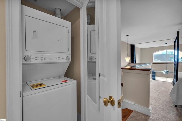 laundry room with carpet floors and stacked washer / dryer