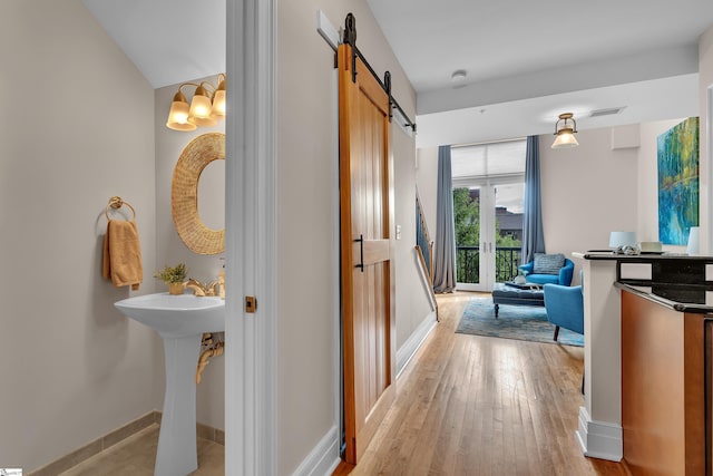 hall featuring a barn door and light hardwood / wood-style flooring