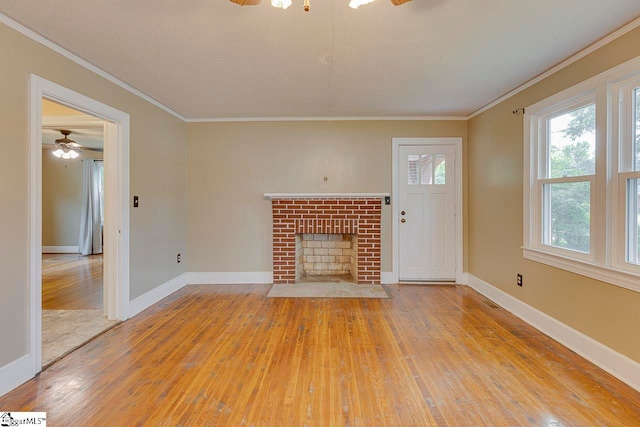 unfurnished living room featuring a fireplace, light hardwood / wood-style flooring, ceiling fan, and crown molding