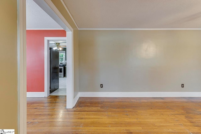 spare room featuring a textured ceiling, light hardwood / wood-style flooring, ceiling fan, and crown molding