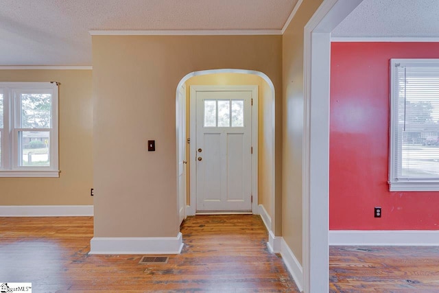 entryway featuring hardwood / wood-style floors, crown molding, and a textured ceiling