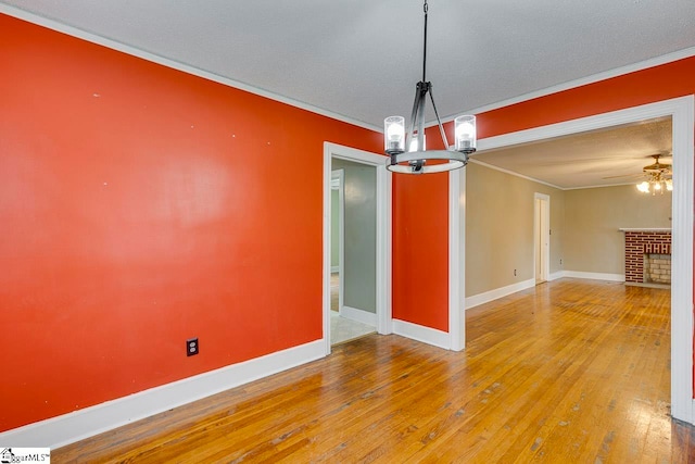 unfurnished dining area featuring a textured ceiling, hardwood / wood-style flooring, ornamental molding, and a fireplace