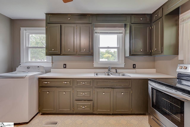 kitchen featuring stainless steel electric range, a wealth of natural light, sink, and washer / dryer