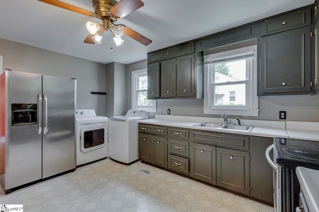 clothes washing area with ceiling fan, a wealth of natural light, separate washer and dryer, and sink