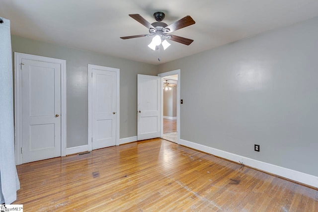 unfurnished bedroom with light hardwood / wood-style floors, ceiling fan, and two closets