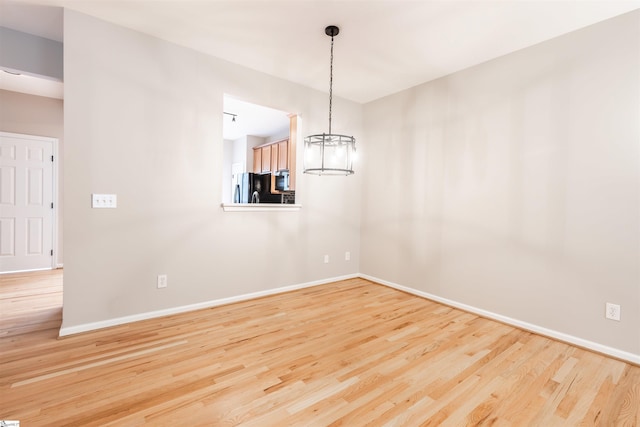 empty room with light hardwood / wood-style flooring and an inviting chandelier