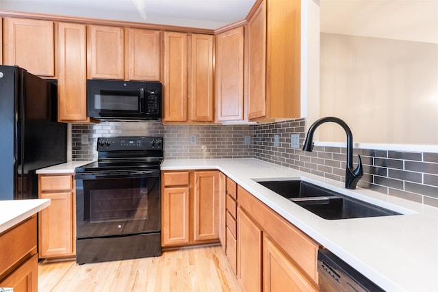 kitchen featuring light hardwood / wood-style flooring, sink, decorative backsplash, and black appliances