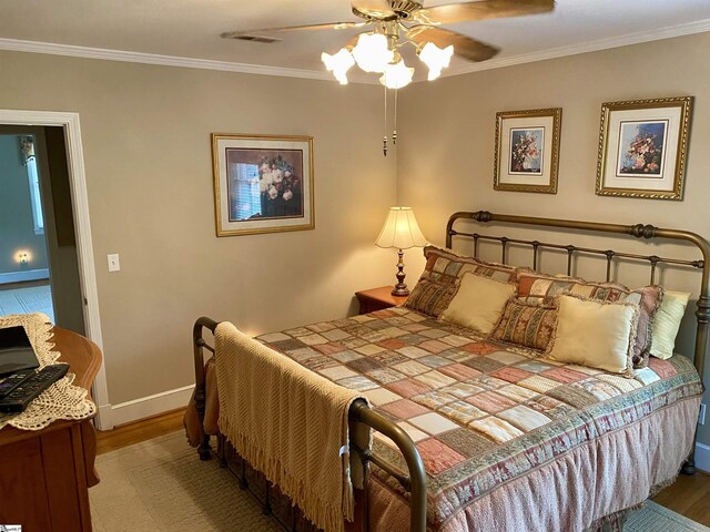 bedroom featuring ornamental molding, wood-type flooring, and ceiling fan