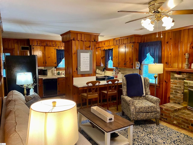 living room featuring ornamental molding, wooden walls, ceiling fan, and a fireplace