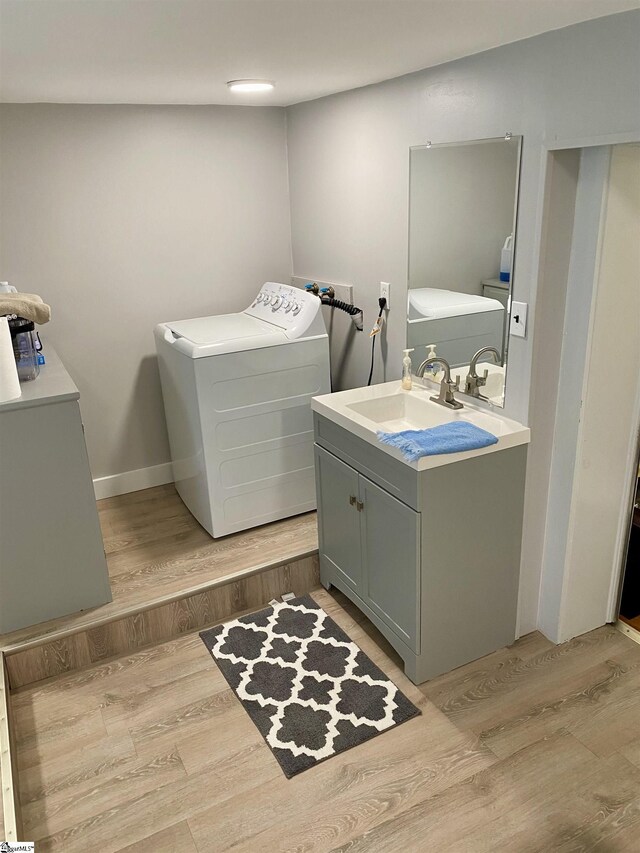 bathroom with vanity, hardwood / wood-style floors, and washer / dryer