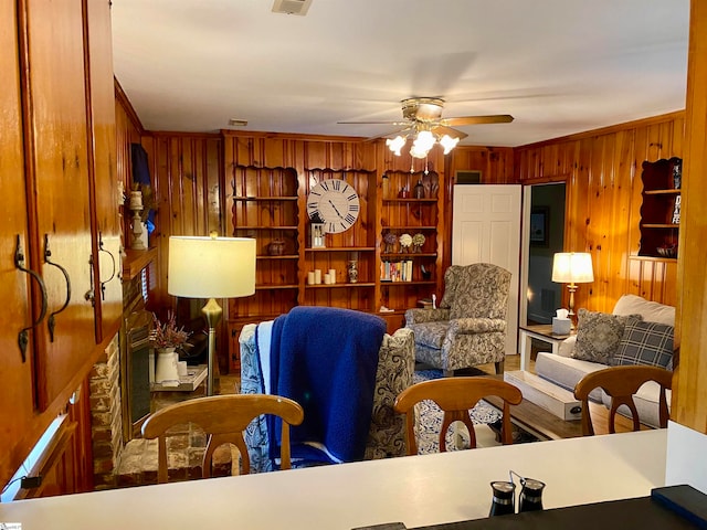 living room with ornamental molding, wooden walls, and ceiling fan