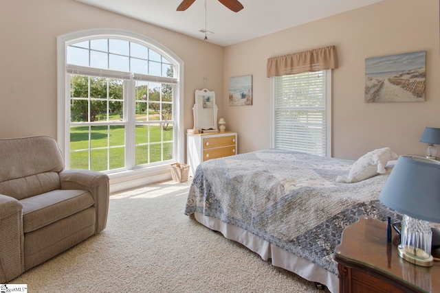 carpeted bedroom featuring multiple windows and ceiling fan