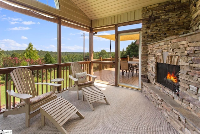 sunroom / solarium featuring vaulted ceiling and an outdoor stone fireplace