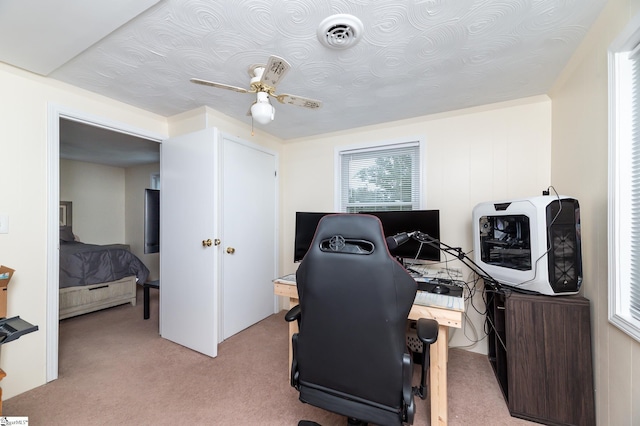 carpeted office featuring ceiling fan and a healthy amount of sunlight