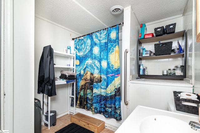 bathroom with a textured ceiling, tile patterned flooring, and curtained shower