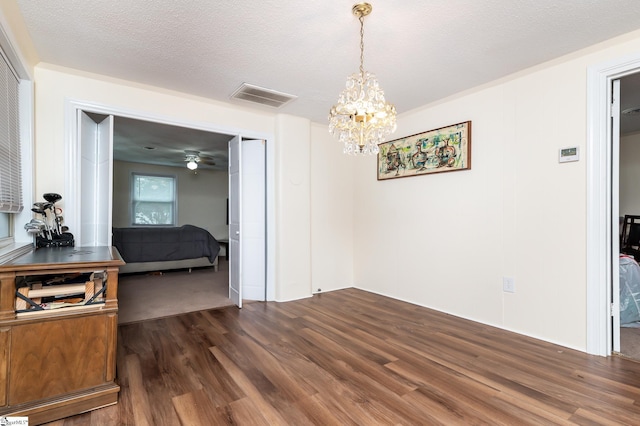 dining space with ceiling fan with notable chandelier, a textured ceiling, and dark hardwood / wood-style flooring