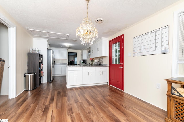 kitchen with dark wood-type flooring, white cabinets, stainless steel refrigerator, pendant lighting, and a textured ceiling