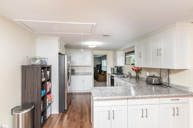 kitchen with a textured ceiling, appliances with stainless steel finishes, kitchen peninsula, and white cabinetry