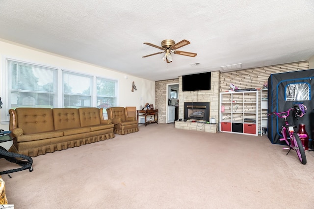 living room featuring ceiling fan, a textured ceiling, a fireplace, and carpet