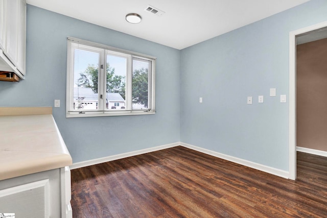 unfurnished dining area with dark wood-type flooring