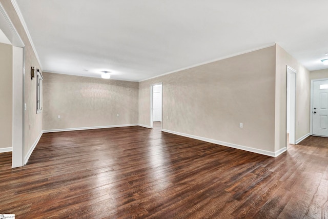 empty room with dark hardwood / wood-style floors and crown molding