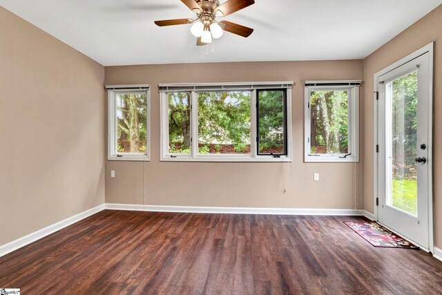 empty room featuring ceiling fan, dark hardwood / wood-style floors, and plenty of natural light