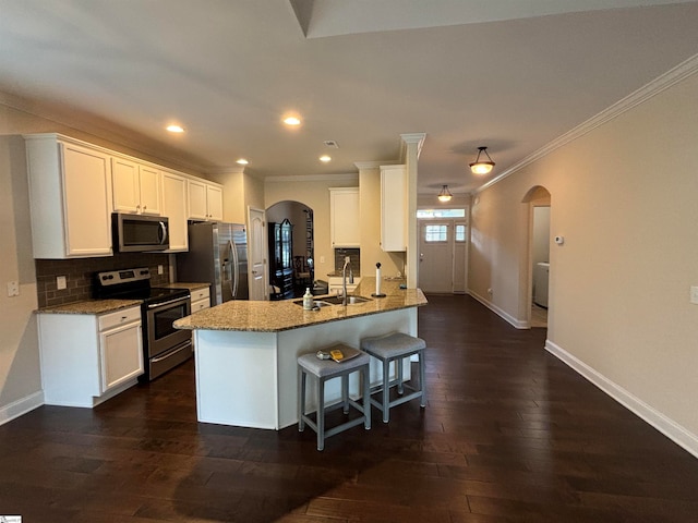 kitchen with appliances with stainless steel finishes, a kitchen breakfast bar, light stone counters, dark hardwood / wood-style floors, and sink