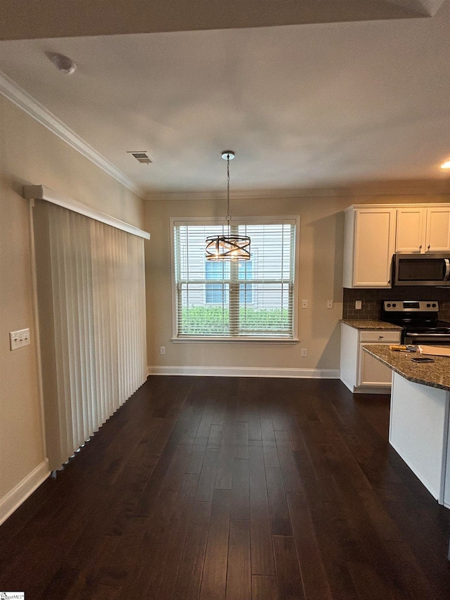 kitchen featuring appliances with stainless steel finishes, white cabinetry, dark wood-type flooring, dark stone counters, and a chandelier