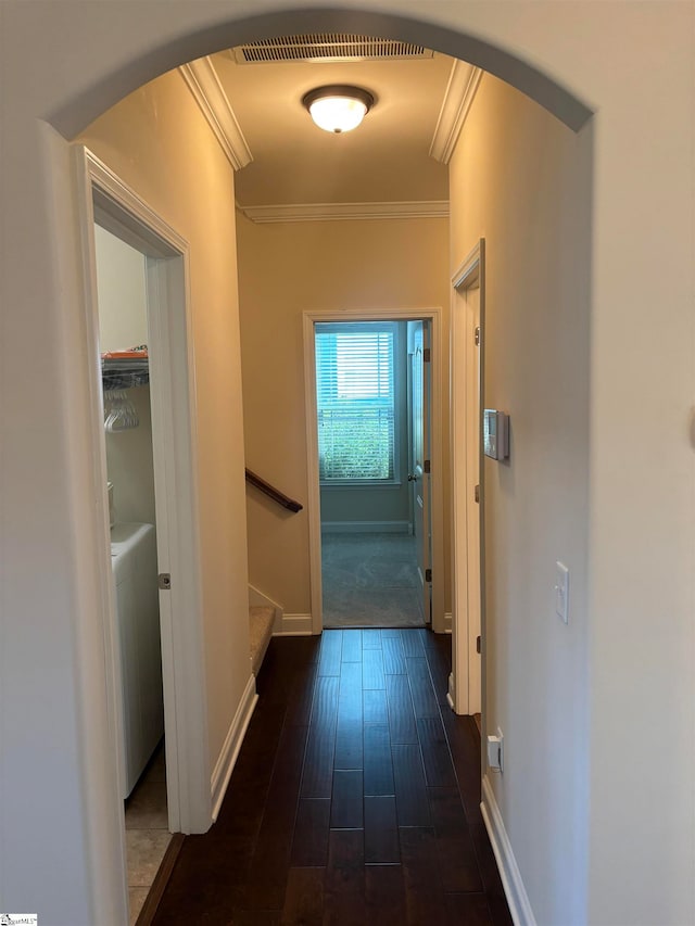 hallway featuring dark hardwood / wood-style floors, crown molding, and washer / dryer