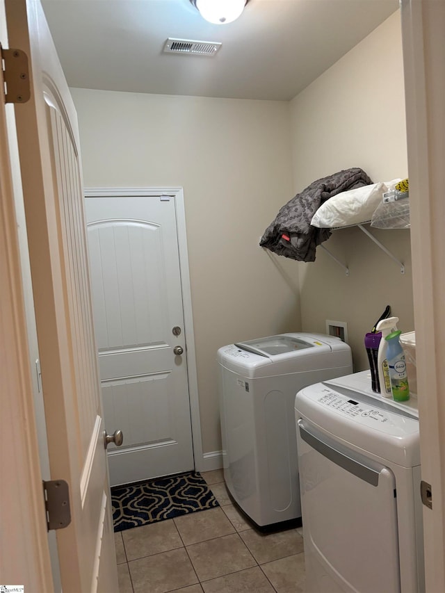 clothes washing area featuring light tile patterned floors and separate washer and dryer