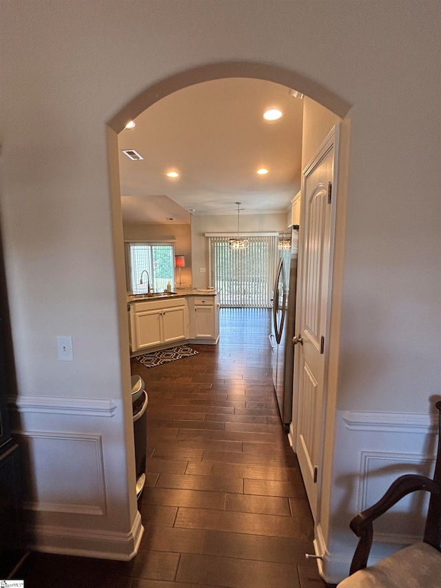 kitchen with dark hardwood / wood-style floors, sink, white cabinetry, stainless steel refrigerator, and decorative light fixtures