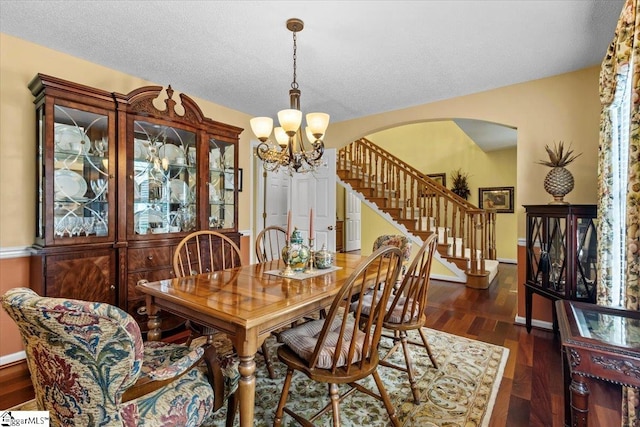 dining space featuring a textured ceiling, dark hardwood / wood-style flooring, and a notable chandelier