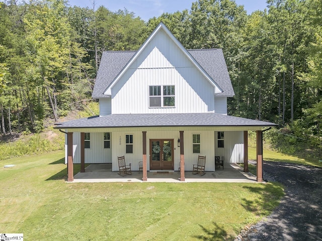 exterior space with a lawn, a shingled roof, a patio area, and french doors