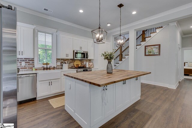 kitchen featuring white cabinets, wooden counters, a sink, and stainless steel appliances