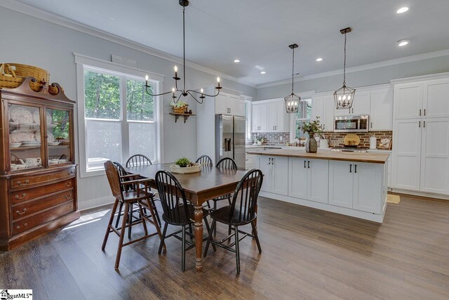 dining space with dark wood finished floors, baseboards, ornamental molding, recessed lighting, and an inviting chandelier