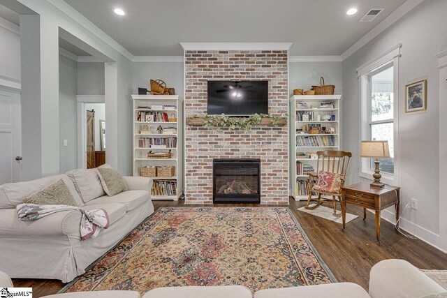 living room with visible vents, a fireplace, wood finished floors, and crown molding