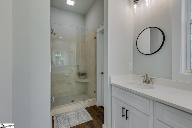 bathroom featuring a shower stall, wood finished floors, and vanity