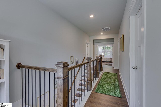 corridor featuring an upstairs landing, wood finished floors, baseboards, visible vents, and recessed lighting