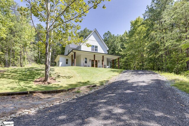 modern inspired farmhouse featuring driveway, a front lawn, and a porch
