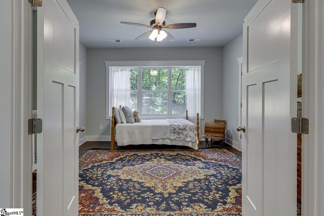 bedroom with wood finished floors, baseboards, ceiling fan, and visible vents