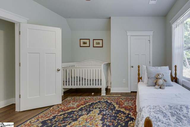 bedroom featuring visible vents, baseboards, lofted ceiling, and wood finished floors