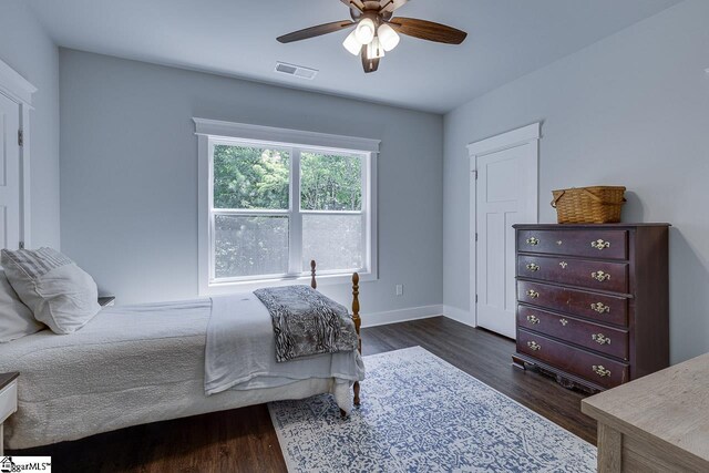 bedroom featuring dark wood finished floors, baseboards, visible vents, and ceiling fan