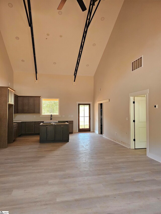 unfurnished living room with ceiling fan, high vaulted ceiling, and light hardwood / wood-style flooring