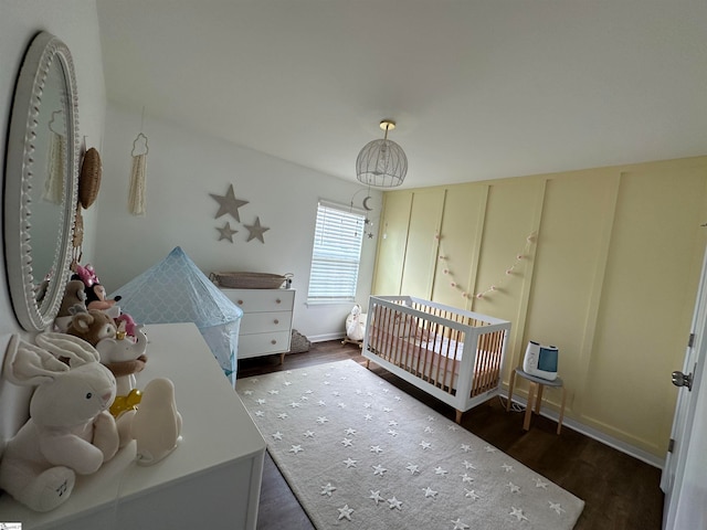 bedroom featuring a nursery area, heating unit, and dark wood-type flooring