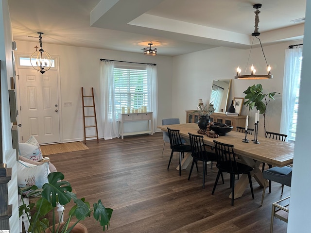 dining area with a tray ceiling, dark hardwood / wood-style floors, and a chandelier