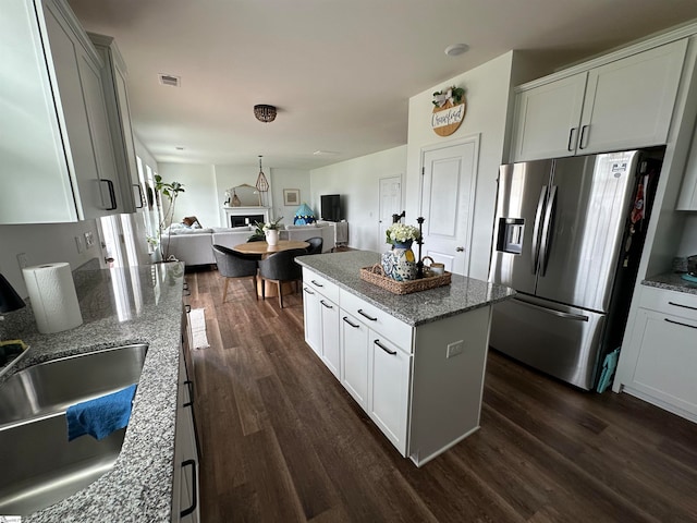 kitchen featuring light stone countertops, dark hardwood / wood-style flooring, stainless steel fridge with ice dispenser, and a kitchen island