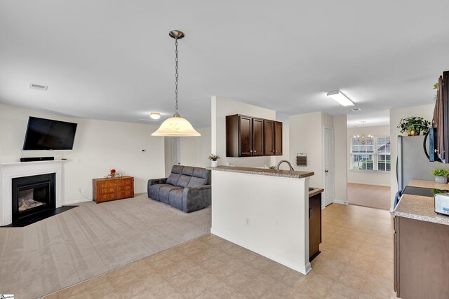 kitchen featuring dark brown cabinets, a notable chandelier, decorative light fixtures, and light stone counters