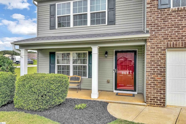 view of exterior entry featuring a porch and a garage